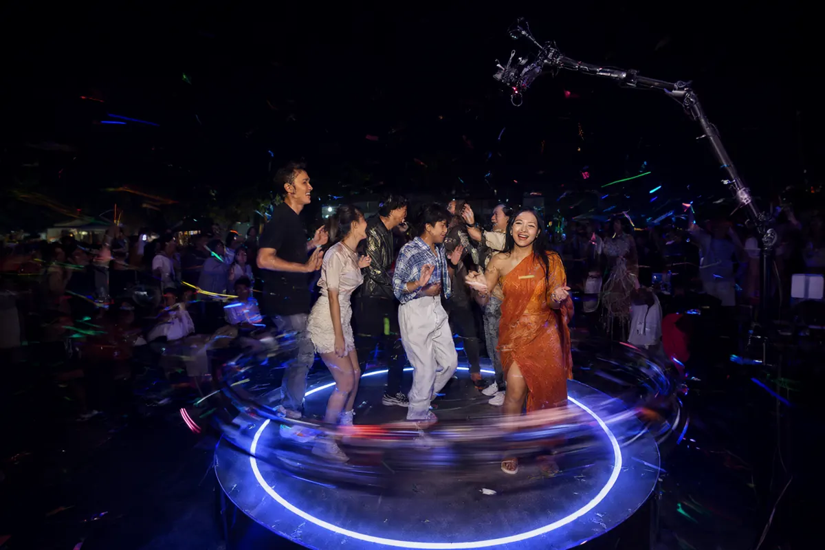 Tiga sahabat menari di platform video booth 360 dengan lampu LED berwarna dan confetti