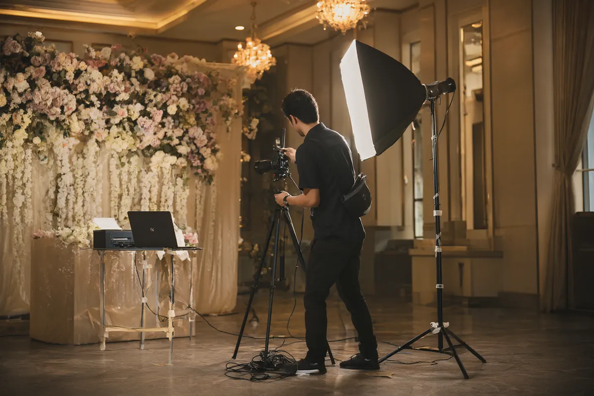 Operator photobooth memasang lampu softbox di ballroom pernikahan sebelum tamu datang
