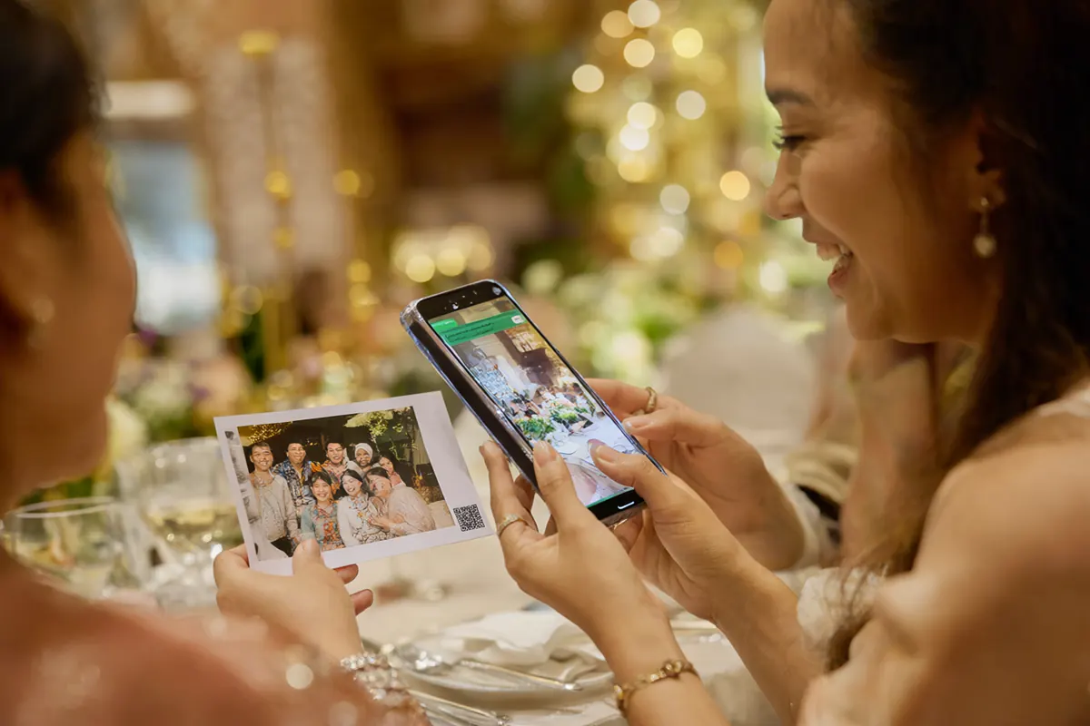 Tamu memindai kode QR di foto cetak dengan ponsel untuk mengunduh versi digital